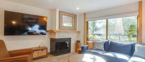 Una sala moderna con chimenea, un televisor de pantalla plana grande, un sofá azul y una mesa de centro redonda.