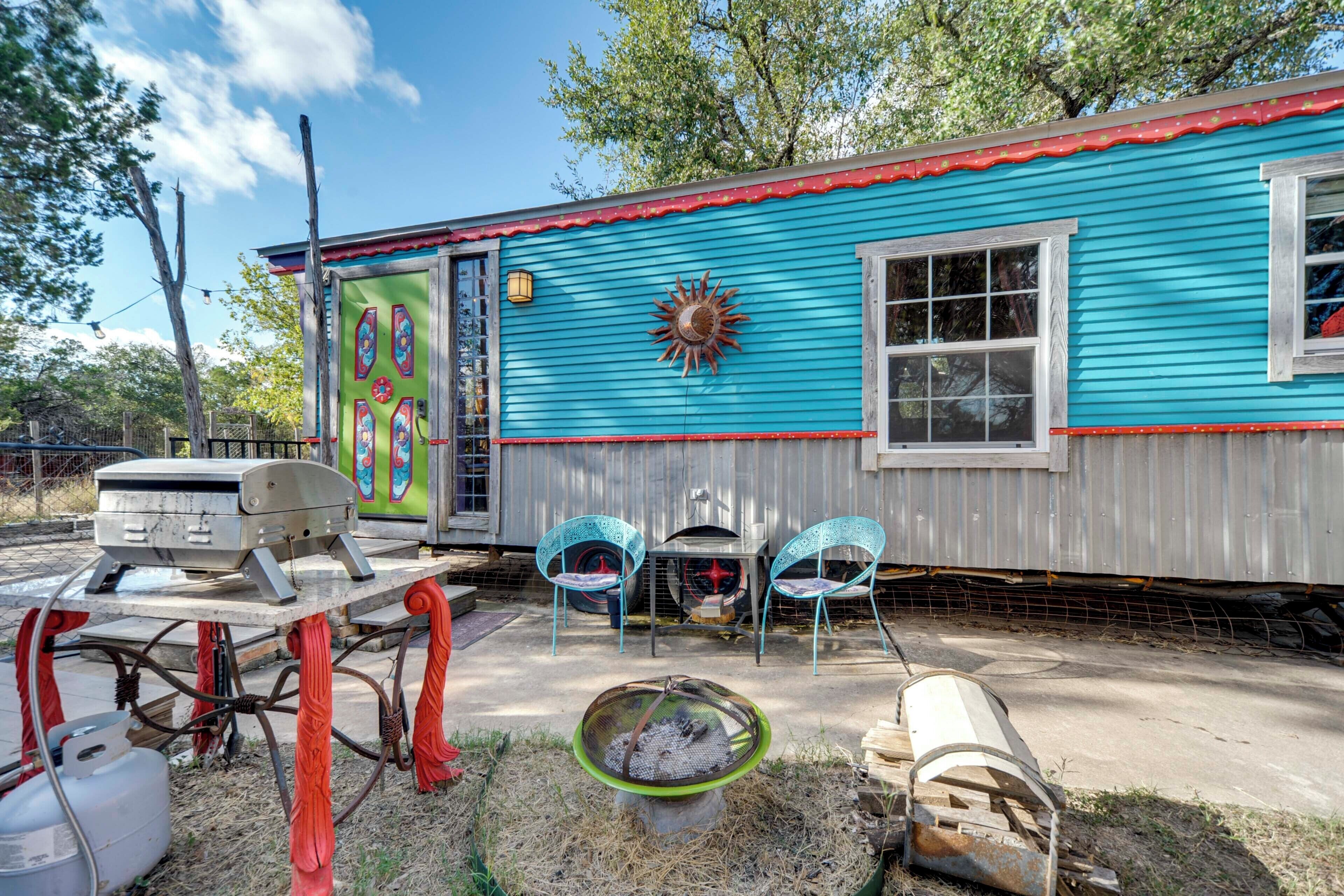 A blue house with a red roof, a large sun decoration, and a grill outside.