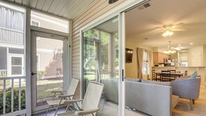 A spacious living area with a sliding glass door leading to a patio, a gray sofa, and a dining area with a table and chairs. - Steps to Pool + Golf! Family Myrtle Beach Retreat (Myrtle Beach)