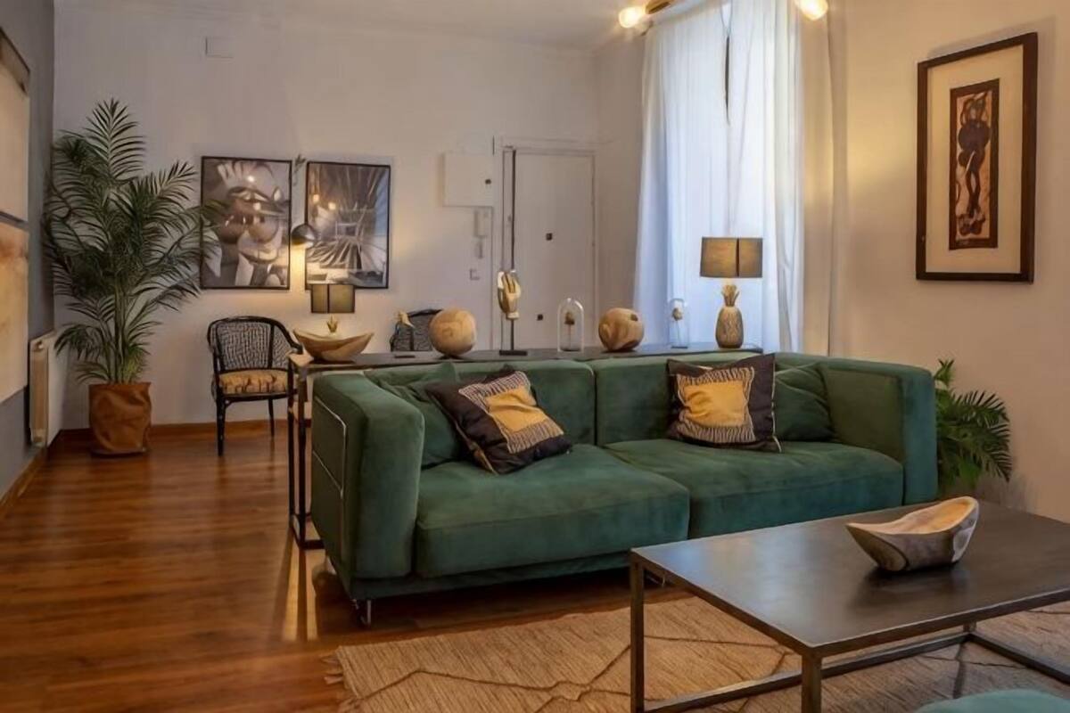 Una sala de estar con un sofá verde, una mesita de centro y una planta en maceta.