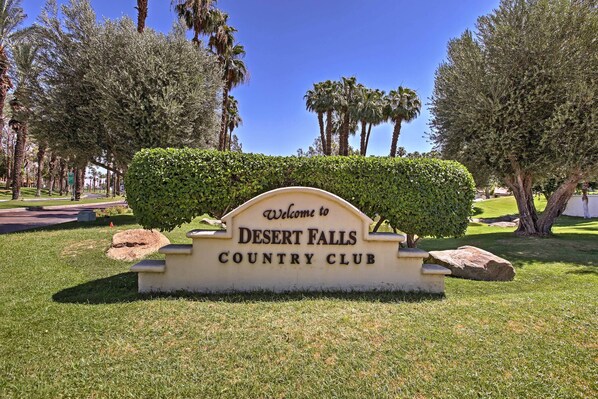 A welcome sign for Desert Falls Country Club surrounded by well-maintained grass and trees. - Golf Course View & Pool Access: Palm Desert Condo (Palm Desert)