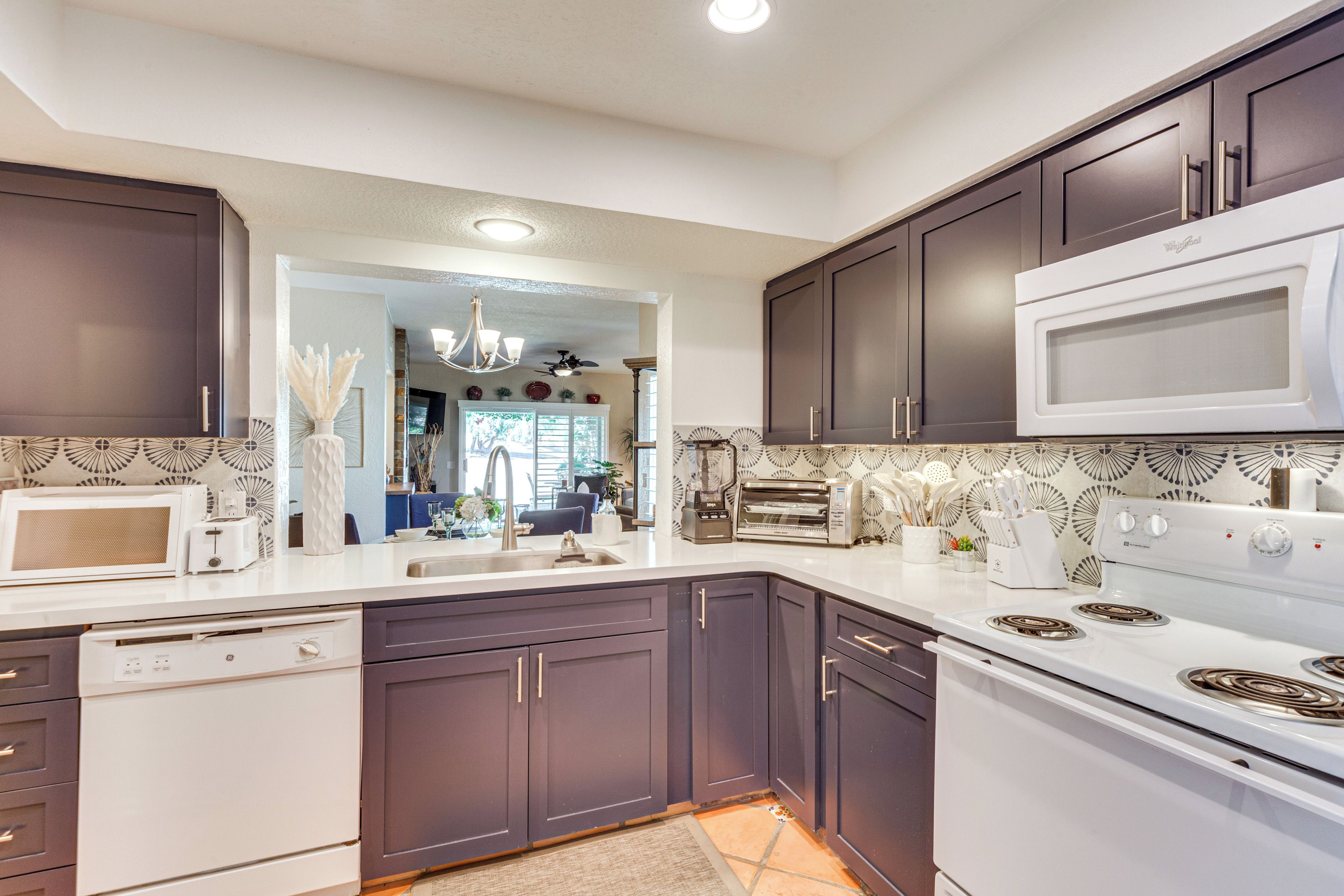 A modern kitchen with dark cabinets, white appliances, and a patterned backsplash.