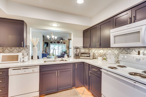 A modern kitchen with dark cabinets, white appliances, and a patterned backsplash.