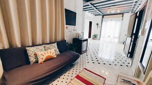 A modern living room with a sofa, patterned cushions, a geometric rug, and a tiled floor. - The Warehouse - Ayutthaya (Ayutthaya)
