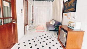 A hallway with a tiled floor, a sofa with cushions, a small table, and a cabinet. - The Warehouse - Ayutthaya (Ayutthaya)