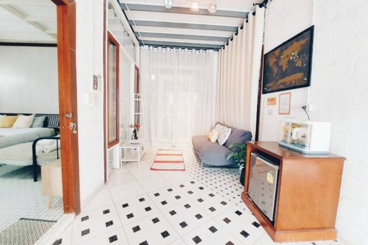 Una sala de estar con un sofá, una mesa de centro, un televisor y un suelo estampado.