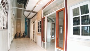 A corridor with a tiled floor, a bicycle, and a door leading to a room with a window. - The Warehouse - Ayutthaya (Ayutthaya)