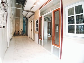 A corridor with a tiled floor, a bicycle, and a door leading to a room with a window. - The Warehouse - Ayutthaya (Ayutthaya)