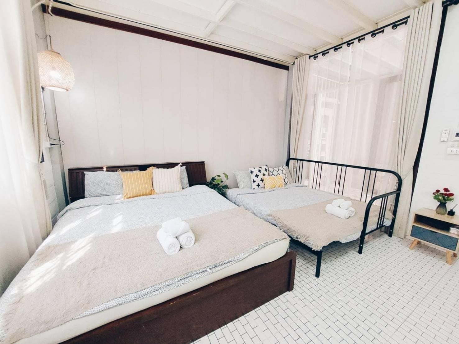 Une chambre double avec deux lits, une table de chevet, une lampe et une fenêtre avec des rideaux.