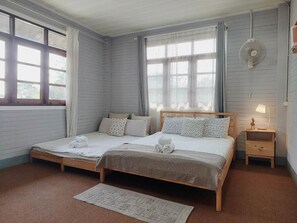 Ein Doppelbett mit Holzrahmen, zwei Nachttische, eine kleine Nachttischlampe und ein Fenster mit Vorhängen.