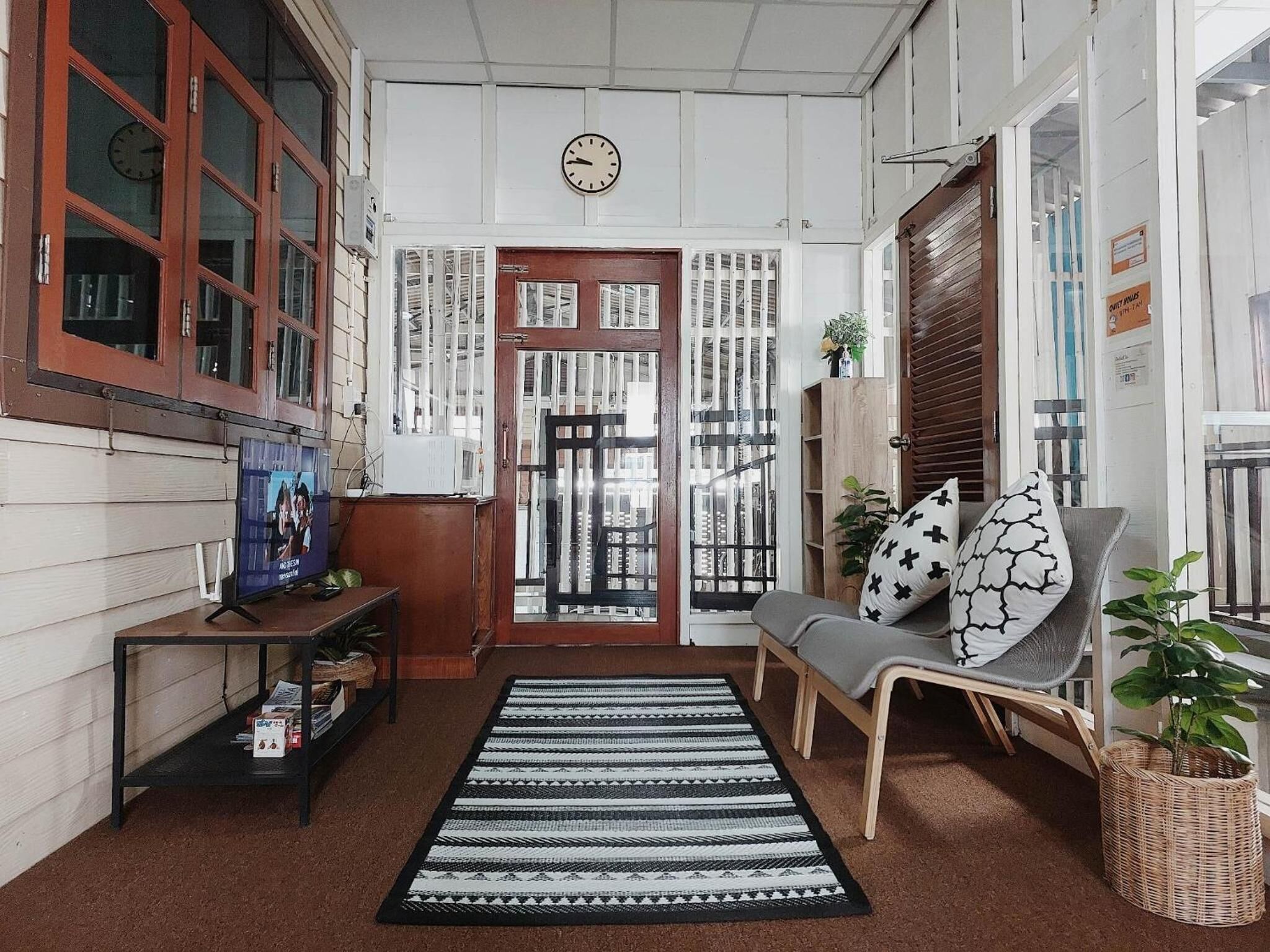 Um interior acolhedor com um sofá, uma televisão e um tapete estampado.