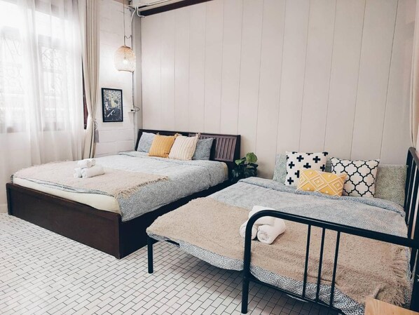 A bedroom with two beds, a window with sheer curtains, a hanging light fixture, and a framed picture on the wall. - The Warehouse - Ayutthaya (Ayutthaya)