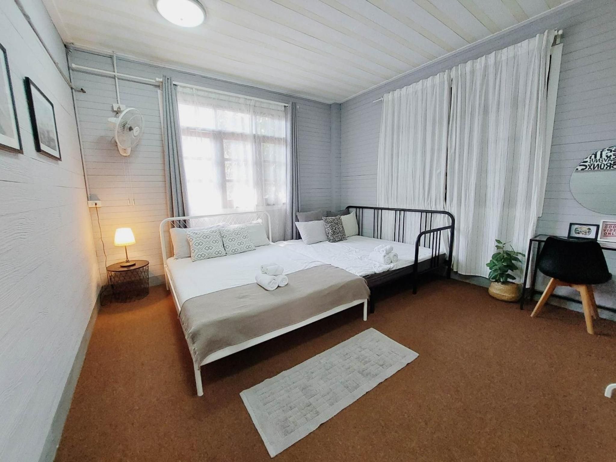 A bedroom with a bed, bedside table, lamp, and a window with curtains.