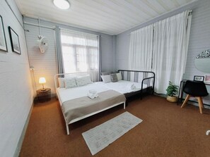 A bedroom with a bed, bedside table, lamp, and a window with curtains. - The Warehouse - Ayutthaya (Ayutthaya)