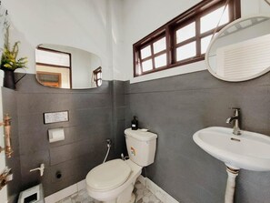 A bathroom with a toilet, sink, mirror, and a window. - The Warehouse - Ayutthaya (Ayutthaya)