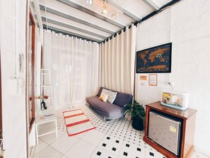 A compact living space with a sofa, a small table, a potted plant, and a world map on the wall. - The Warehouse - Ayutthaya (Ayutthaya)