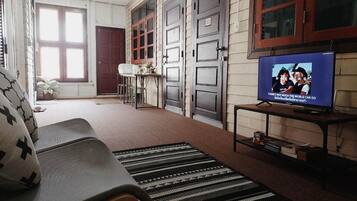 Una sala de estar con un sofá, un televisor y una alfombra estampada.
