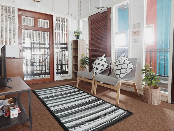 A living room with a sofa, a coffee table, a TV, a bookshelf, and a patterned rug. - The Warehouse - Ayutthaya (Ayutthaya)