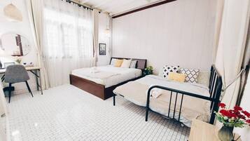 Quarto com cama, mesas de cabeceira, escrivaninha e uma cadeira.