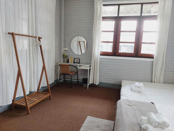 A bedroom with a bed, a desk, a chair, a hanging swing, and a window.