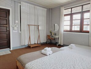 A room with a bed, a desk, a chair, a hanging clothes rack, and a window with curtains. - The Warehouse - Ayutthaya (Ayutthaya)