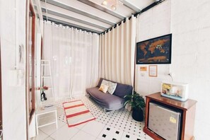 A compact living space with a sofa, a small table, a television, and a world map on the wall. - The Warehouse - Ayutthaya (Ayutthaya)