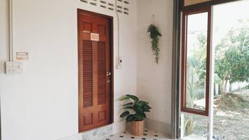 Een kamer met een houten deur, een plant in pot en een betegelde vloer.