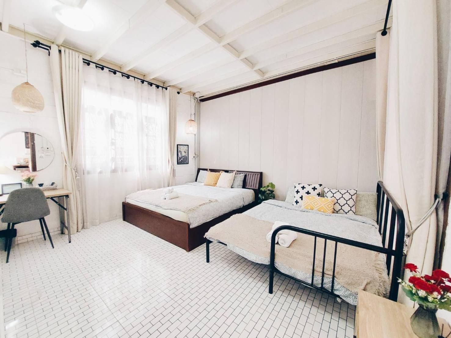 A bedroom with two beds, a desk, a chair, and a mirror.