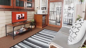 A living room with a television, a sofa, a patterned rug, and a window with curtains.
