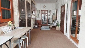 A hallway with a wooden table, chairs, a clock, and a door leading to another room.