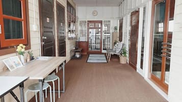 A hallway with a wooden table, chairs, a clock, and a door leading to another room.