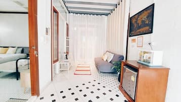 Hotellihuone, jossa on sänky, sohva, televisio ja työpöytä.