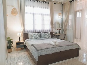 A hotel room with a large bed, a bedside table, a lamp, a mirror, and a potted plant. - The Warehouse - Ayutthaya (Ayutthaya)
