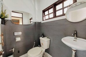 Een badkamer met toilet, wastafel, spiegel en raam.