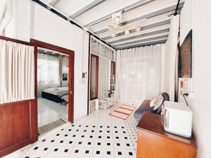 A hotel room with a bed, a desk, a chair, a radiator, and a window with curtains. - The Warehouse - Ayutthaya (Ayutthaya)