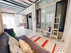 A modern living room with a sofa, a coffee table, and a patterned rug. There is a sliding glass door leading to a balcony with a motorcycle parked outside. - The Warehouse - Ayutthaya (Ayutthaya)