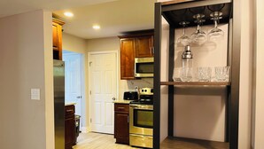 A modern kitchen with wooden cabinets, stainless steel appliances, and a wine glass display.