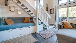 Un salon chaleureux avec un escalier, un canapé bleu, un canapé gris et un plancher en bois.