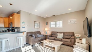 A living room with a sofa set, a coffee table, and a kitchen area with wooden cabinets and a refrigerator. - 2 Blocks to Beach: Cozy Retreat in Wildwood! (Wildwood)