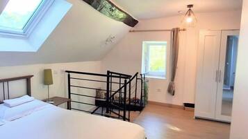 Un dormitorio con cama, tragaluz y vistas a un balcón.