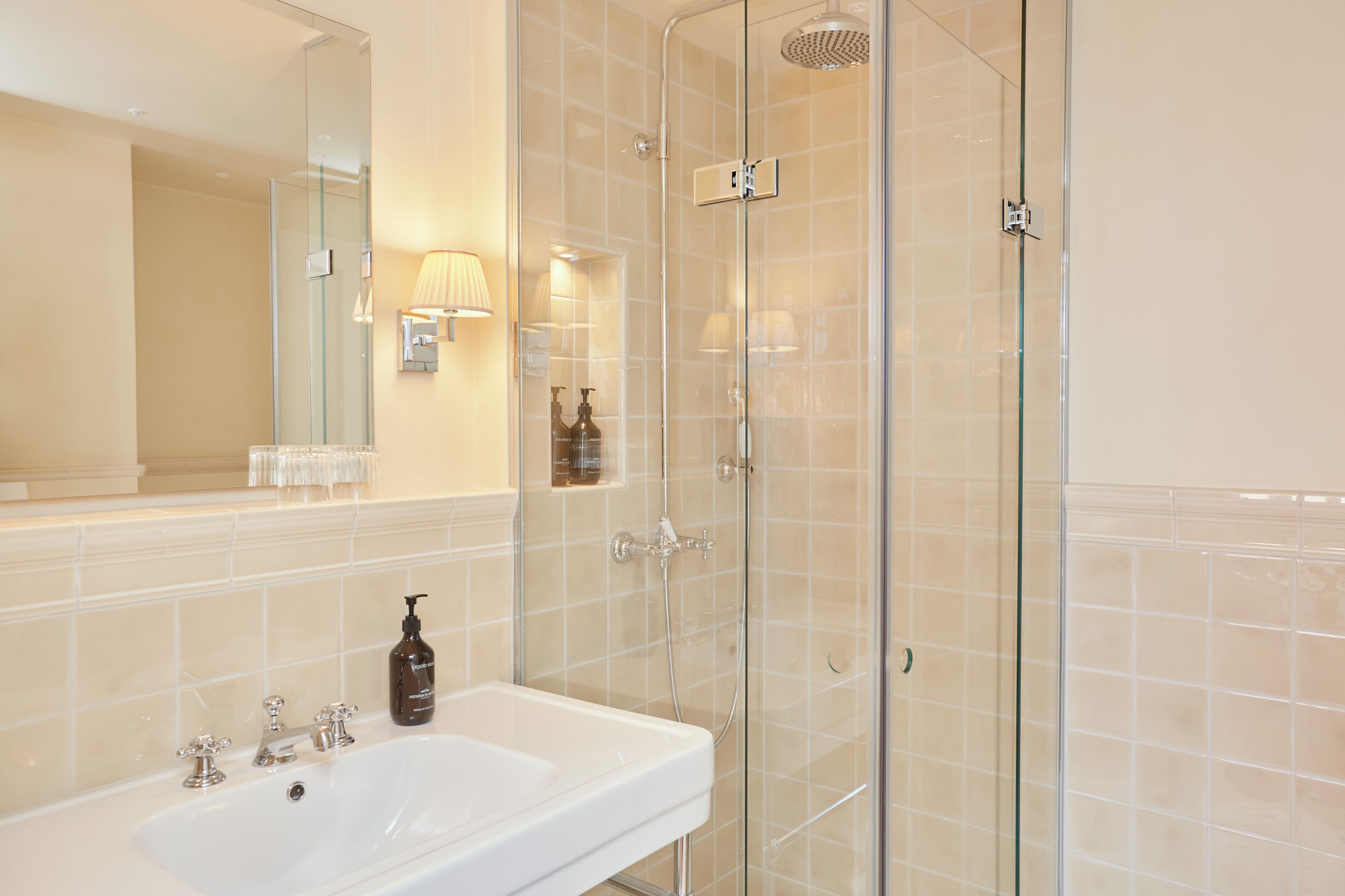 Une salle de bain avec une douche à parois de verre, un lavabo blanc et un miroir au-dessus du lavabo.