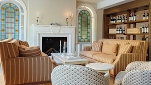 A living room with striped sofas, a fireplace, and a wine rack. -  Henrik's Hotel (Copenhagen)
