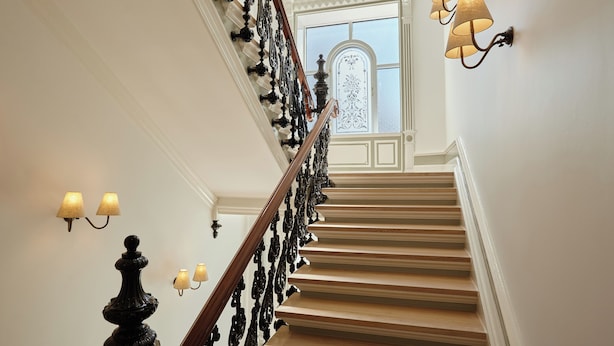 A grand staircase with ornate railings and wall sconces. -  Henrik's Hotel (Copenhagen)