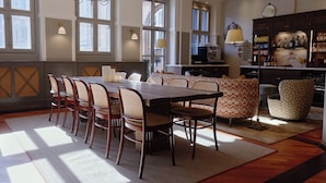 A dining area with a long table and chairs, a sofa, and a bar area with shelves of bottles and glasses. -  Henrik's Hotel (Copenhagen)
