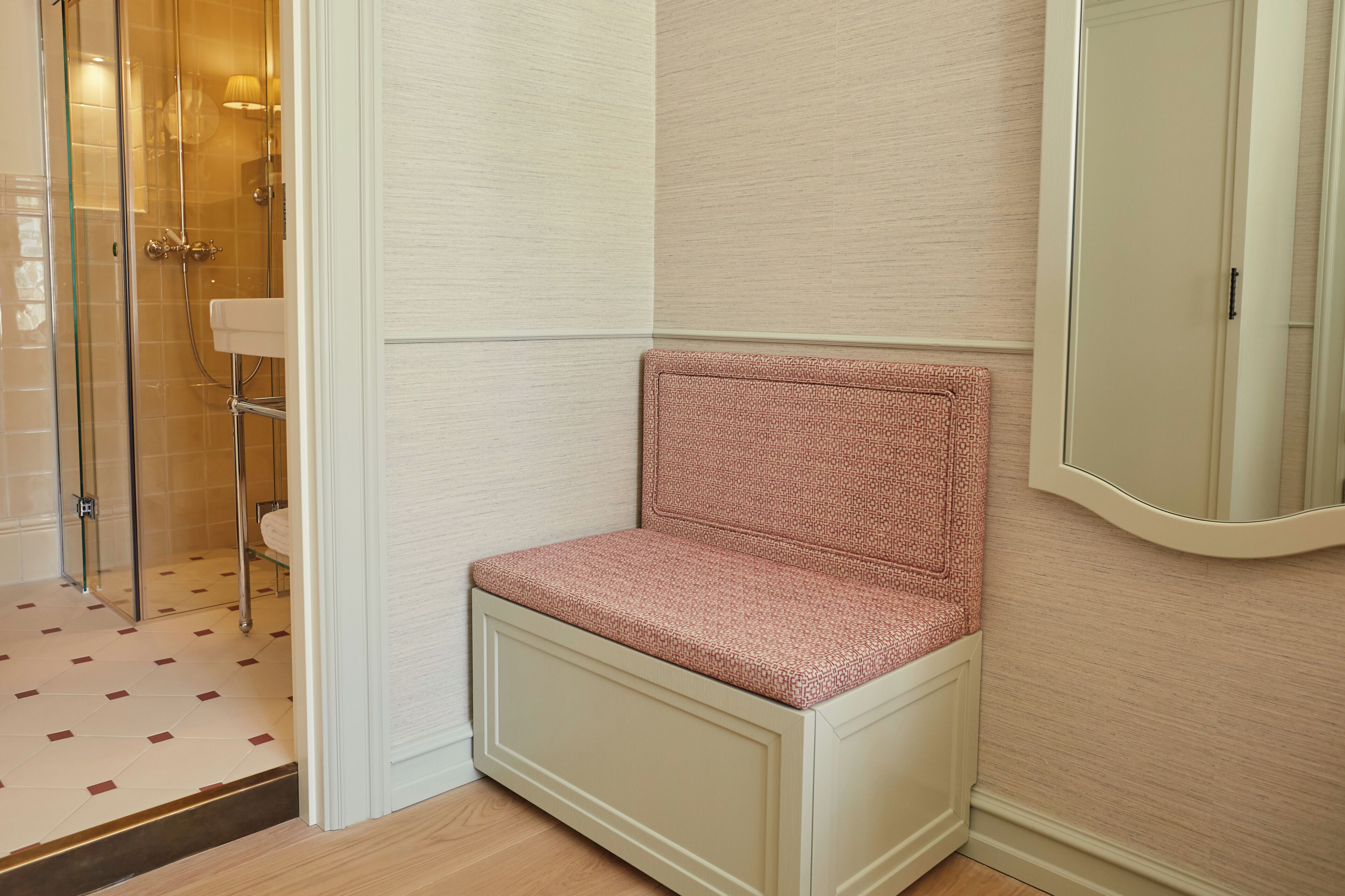 A corner bathroom with a shower, a sink, and a bench.