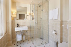 A bathroom with a glass-enclosed shower, a sink with a mirror, and a toilet. -  Henrik's Hotel (Copenhagen)