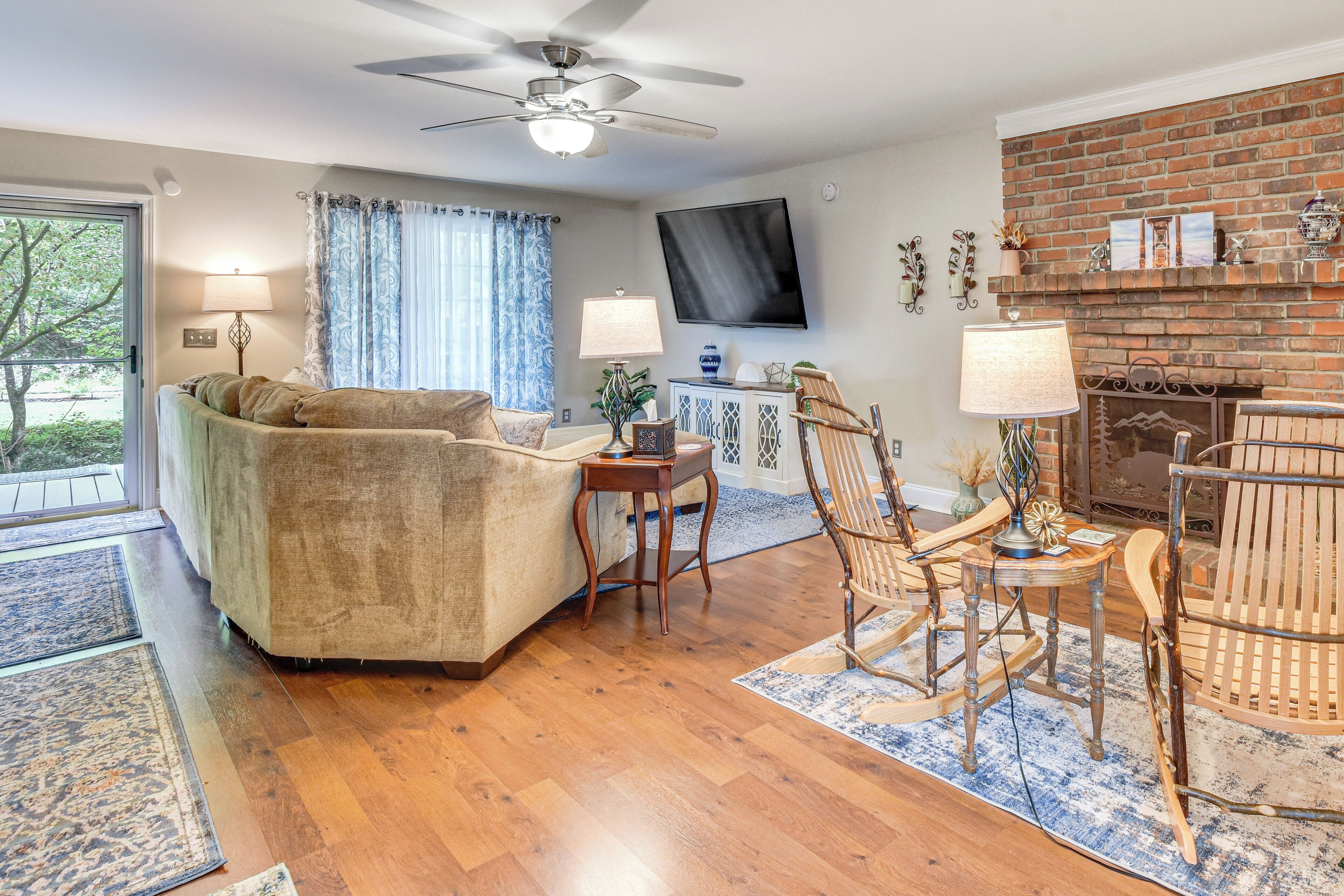 A living room with a sofa, a wooden rocking chair, a fireplace, and a television mounted on the wall.