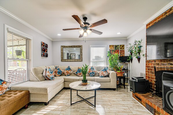A living room with a sectional sofa, a round coffee table, a ceiling fan, and a fireplace. - Walk to Historic Dtwn Burlington: Home w/ Yard (Burlington)