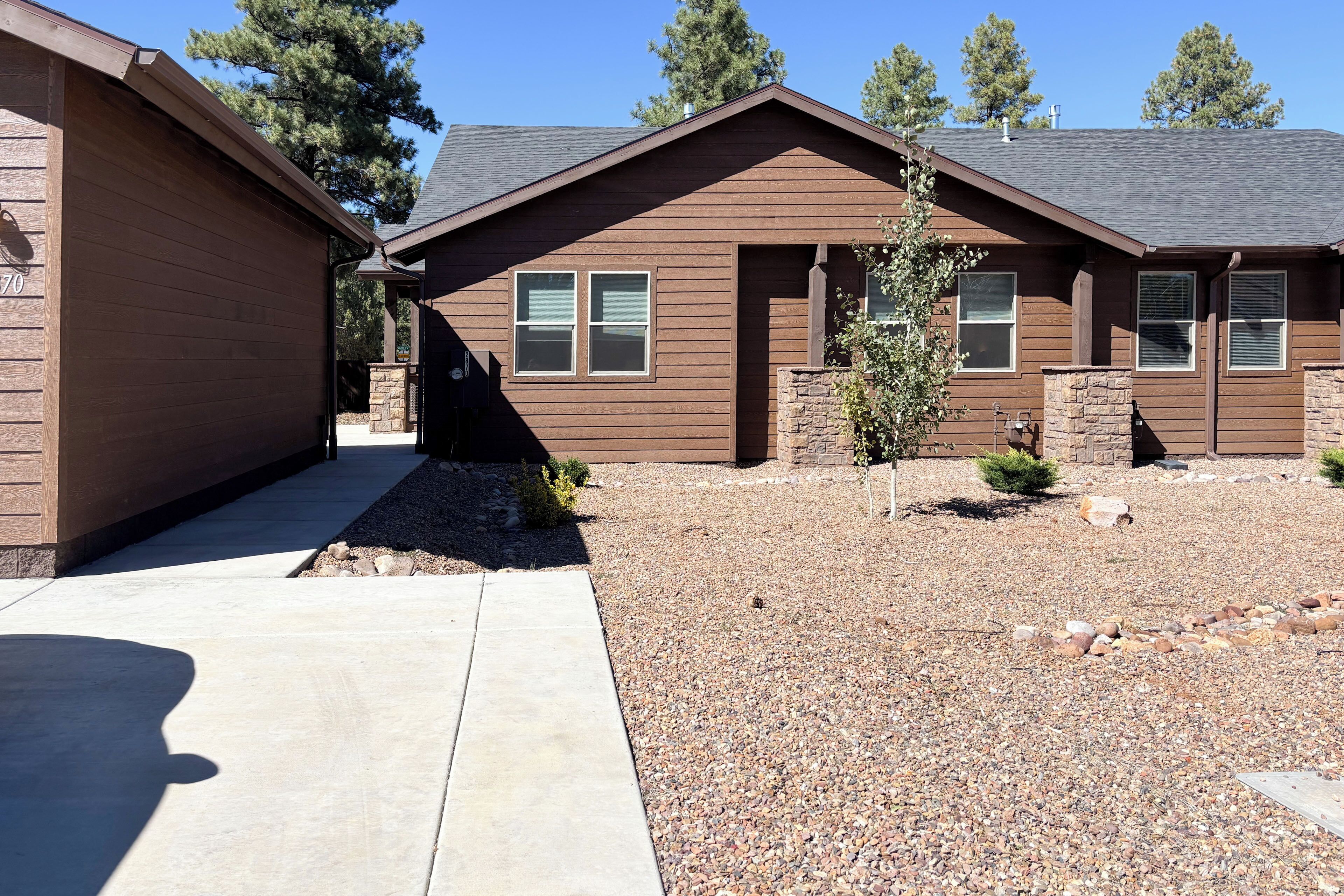 A two-story house with a stone foundation and a gravel driveway.