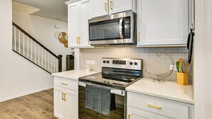 Una cocina con armarios blancos, electrodomésticos de acero inoxidable y suelo de madera.